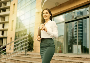 Young woman holding coffee as she leaves tech office